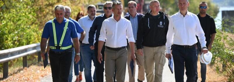 Paks, 2026. augusztus 15. Magyar Péter miniszterelnök (k) paksi sajtótájékoztatójára érkezik az MVM Paksi Atomerőmű közelében 2026. augusztus 15-én. Mellette Gacsályi József, az Országos Vízügyi Főigazgatóság műszaki főigazgató-helyettese (b) és Kádár Pál, a Védelmi Igazgatási Hivatal főigazgatója (j). Mögöttük Ruszin-Szendi Romulusz honvédelmi miniszter, Ruff Bálint, a Miniszterelnökséget vezető miniszter, Kapitány István gazdasági és energetikai miniszter és Tóth Péter nemzetbiztonsági főtanácsadó (j-b). Rövidesen megkezdődik a bárkák irányított süllyesztése Paksnál a dunai vízszint emelése érdekében. MTI/Bodnár Boglárka